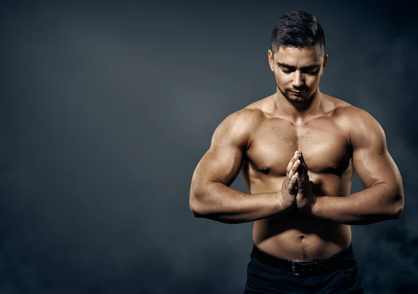 ボディビルダーマン 濃い灰色の背景に強い体と手の筋肉を示す運動選手 瞑想ヨガの練習をするトップレス男性 スポーツマン健康コンセプト — ストック写真