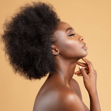 Yüzüne ve boynuna masaj yapan Afrikalı Güzel Kadın 'ın yüz profili. Bej üzerinde Afro Saç Tarzı Mankeni olan Koyu Deri Model. Kadınların Yüz ve Vücut Bakımı Spa Kozmetolojisi