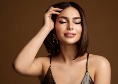 Koyu Kahverengi Üzerine Güzel Kadın Yüzü Portresi. Mükemmel Cilt Makyajlı Moda Modeli ve Bob Saç Tarzı. Kapalı Gözlü, Bronz Dudak Parlatıcısı Gülümseyen Rüya Tarzı Kız
