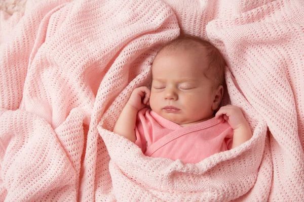 新生婴儿穿着针织毛毯睡觉 可爱的婴儿裹在棉花毛巾里 新出生的小女孩穿着粉色衣服躺在床上休息 小孩儿脸肖像 — 图库照片