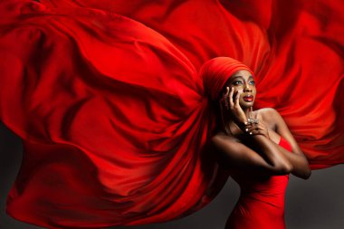 Kırmızı İpek Başörtülü Afrikalı Siyah Kadın. Türbanlı Moda Koyu Derili Moda Model Portresi, Hijab 'da Altın Mücevherler, Gri Arkaplan üzerinde uçan şifon kumaş. Tarz sahibi Arap Güzelliği Kadın Başlığı