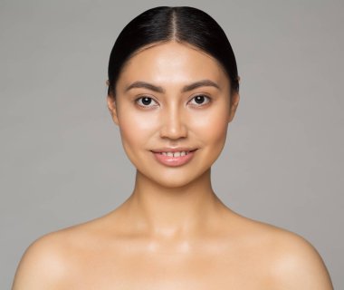 Asya Güzeli. Yüz bakımı. Temiz ve sağlıklı yüz derisi olan mutlu kadın Gray 'in üzerindeki kameraya gülümsüyor. Doğal Makyajlı Çin Modeli. Yakın plan portre. Spa Kozmetolojisi