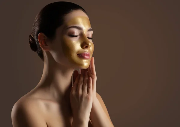 面部剥皮金面具 带着金色高耸脸罩在黑暗背景下的女人 美容师享受护肤温泉美容美发闭眼 妇女抗衰老化妆品 — 图库照片