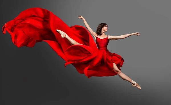 バレリーナダンス 赤いドレスのバレエダンサーがスプリットジャンプします 女性でバレリーナの靴ダンスでシルクガウン飛んで上の風グレースタジオ背景 — ストック写真