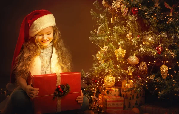 Kerst Kind Opening Aanwezig Naast Kerstboom Happy Girl Santa Hat — Stockfoto