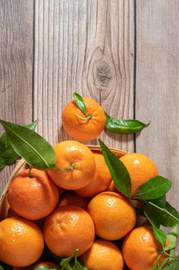 Tahta bir yüzeyde yeni toplanmış mandalinalarla dolu sepet.