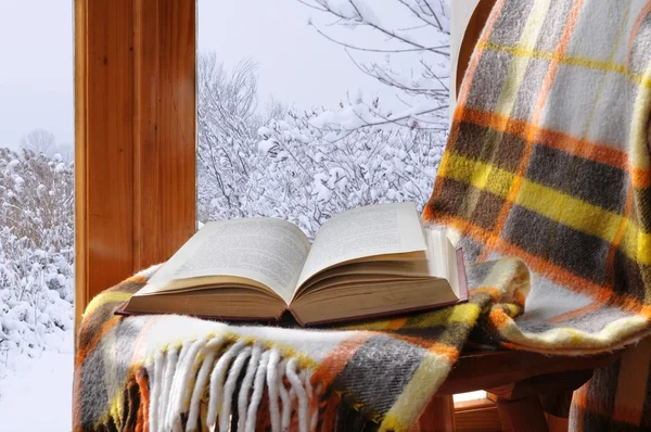Książki na krześle w zimie, w pobliżu okna — Zdjęcie stockowe