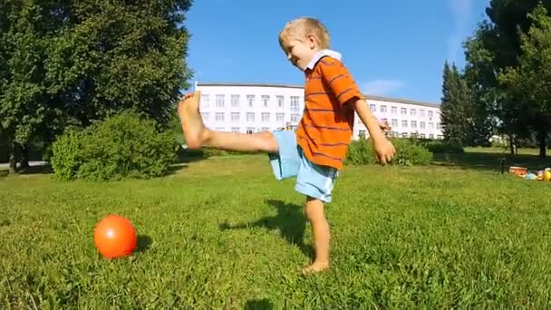 Мальчик играет с мячом в жаркий летний день — стоковое видео