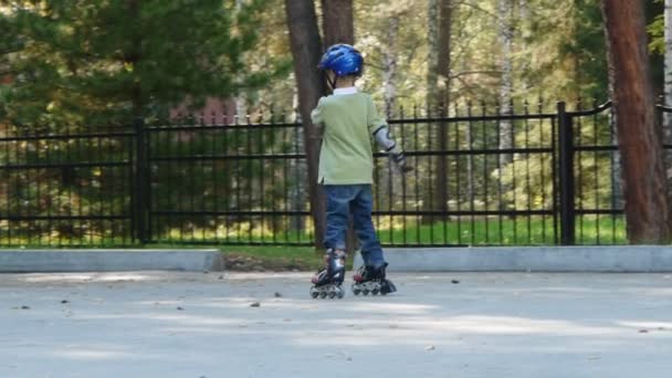 Six years old boy learning to ride on rollerblades — Stock Video