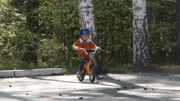 Um rapazinho de capacete a andar de bicicleta. Visão traseira — Vídeo de Stock