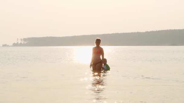 Schwangere Mutter und Kind schwimmen bei Sonnenuntergang im Meer — Stockvideo