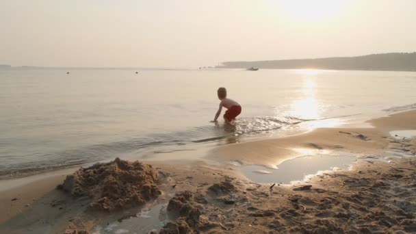 Mały chłopiec bawiący się piaskiem na plaży — Wideo stockowe