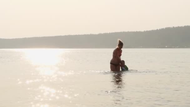 Zwangere moeder en kind zijn zwemmen in de zee bij zonsondergang — Stockvideo