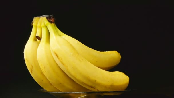 Bando de bananas girando sobre fundo preto — Vídeo de Stock