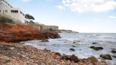 Taşlı bir sahilde dalgalar kopuyor.