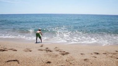 Küçük çocuk kumsalda oynuyor.