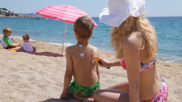 Cuidado del sol en la playa: Madre aplicando sol gritar a su hijo — Vídeo de stock