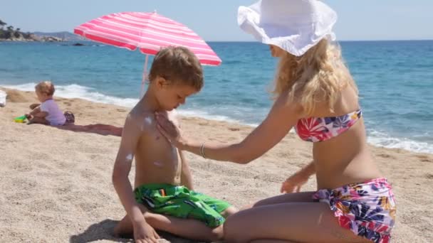 Cuidado del sol en la playa: Madre aplicando sol gritar a su hijo — Vídeo de stock