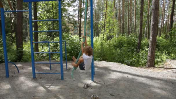 Pojken klättrar ett rep på lekplatsen — Stockvideo