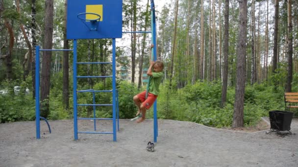 Мальчик забирается на веревку на игровую площадку — стоковое видео