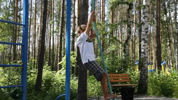 Pojken klättrar ett rep på lekplatsen — Stockvideo