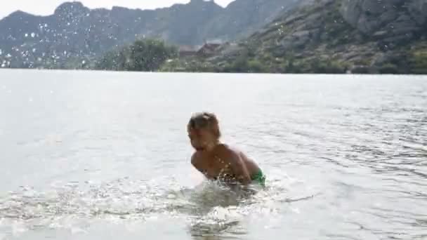 Jongen spatten maken in het bergmeer — Stockvideo