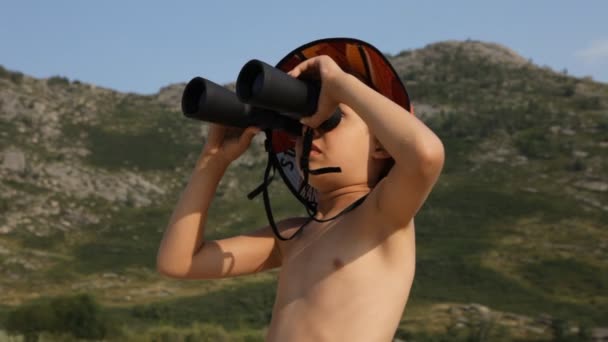 Хлопчик дивиться через бінокль в горах — стокове відео
