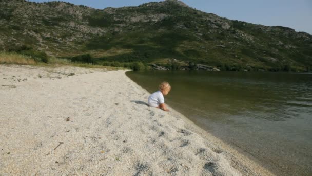 Малыш играет на берегу реки — стоковое видео