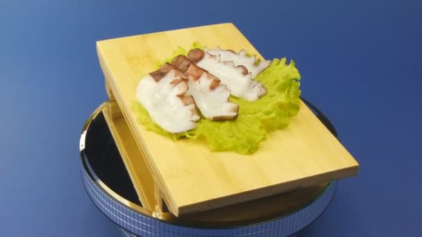 Fresh octopus with green lettuce on wooden plate — Stock Video