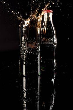 HELSİNGBORG, SWEDEN - 06 Nisan 2022: Bir bardak dolusu Coca Cola 'nın içine düşen bir buz küpünün stüdyo çekimi kola sıçramasıyla sonuçlandı.