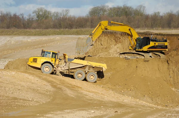黄色的倾卸卡车和挖掘机在砾石坑中工作 — 图库照片