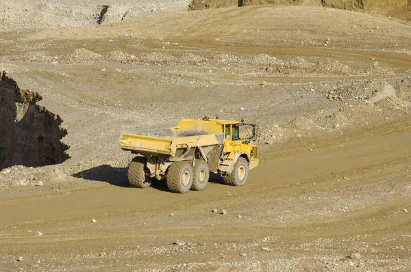 一辆黄色的倾卸卡车在砾石坑中驾驶和工作 — 图库照片