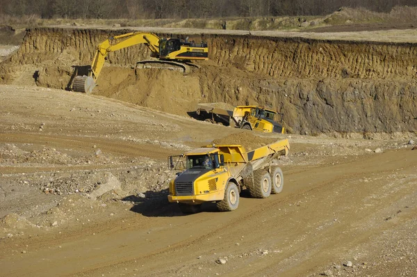 黄色的倾卸卡车和挖掘机在砾石坑中工作 — 图库照片