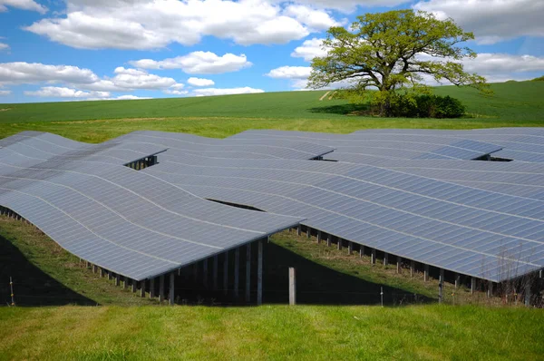 成排的太阳能电池板和带云彩的绿色自然 — 图库照片