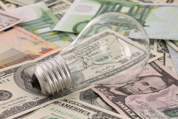Bombilla de luz acostada sobre el dinero —  Fotos de Stock