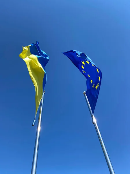 在蓝天的映衬下 在旗杆上挥动乌克兰和欧盟国旗 — 图库照片