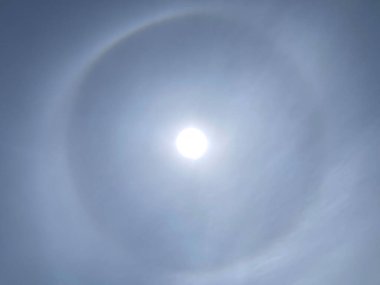 Hafifçe bulutlu bir gökyüzünde yuvarlak halo fenomeni