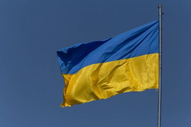 waving Ukrainian flag on flagpole against blue sky