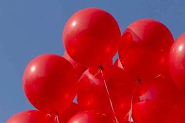 Mavi gökyüzüne karşı bir grup kırmızı balon yakın