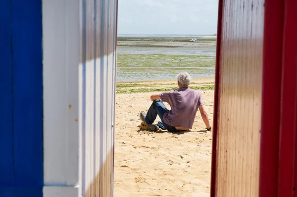 Hombre en la playa frente a cabañas de playa —  Fotos de Stock