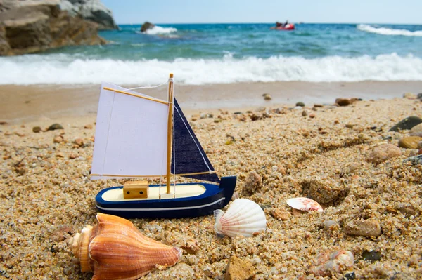 Speelgoed saill boot op het strand — Stockfoto