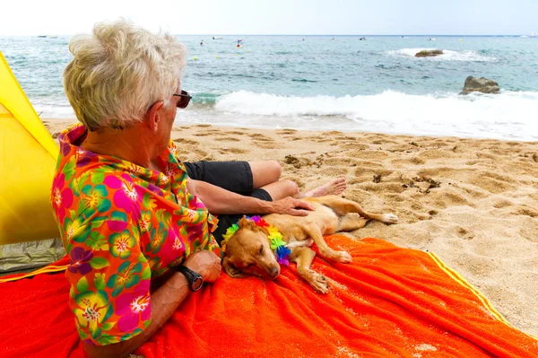 Uomo sdraiato con cane in spiaggia — Foto Stock
