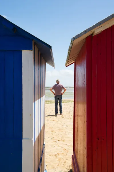 Man on the beach in front of beach huts — Stock Photo, Image