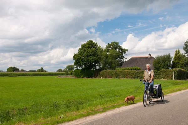 Літній чоловік на велосипеді з собакою — стокове фото