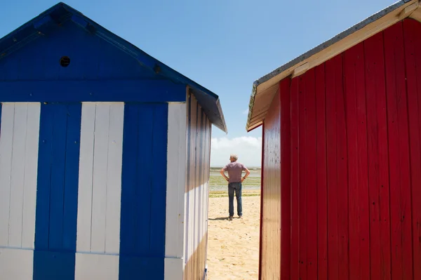 Hombre en la playa frente a cabañas de playa —  Fotos de Stock