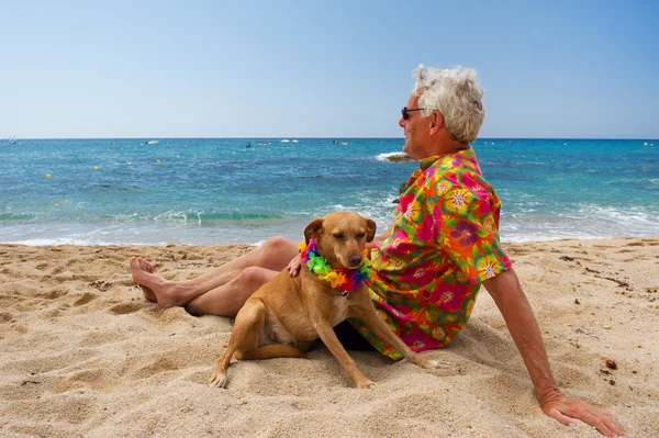 Hombre tendido con perro en la playa — Foto de Stock
