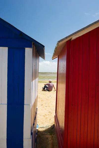 Homme sur la plage devant les cabanes de plage — Photo