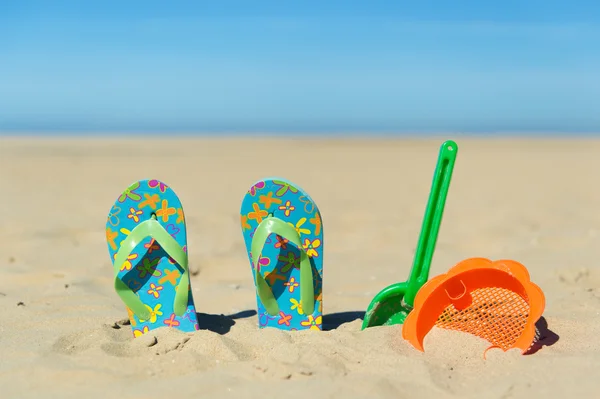 Chanclas y juguetes en la playa —  Fotos de Stock