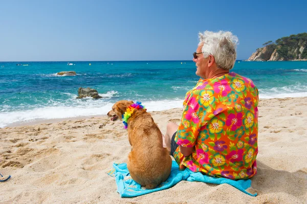 Sahilde köpeği olan yaşlı bir adam. — Stok fotoğraf