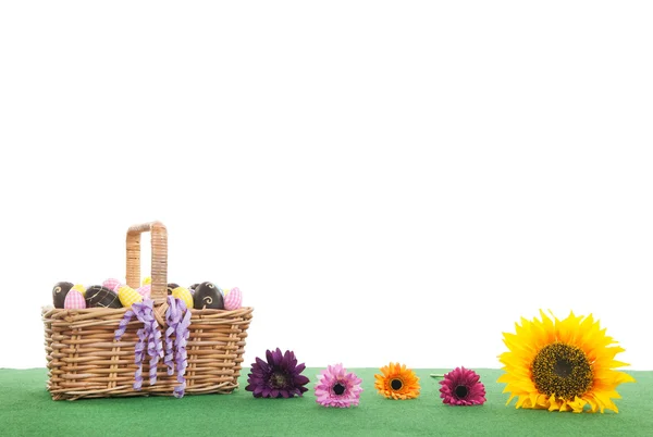 Colorful flowers and basket easter eggs on green grass — Stock Photo, Image